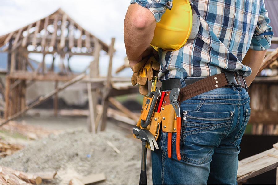 Contractor Insurance - Construction Worker Wearing a Tool Belt, Hands on Hips, Looking over a Job Site